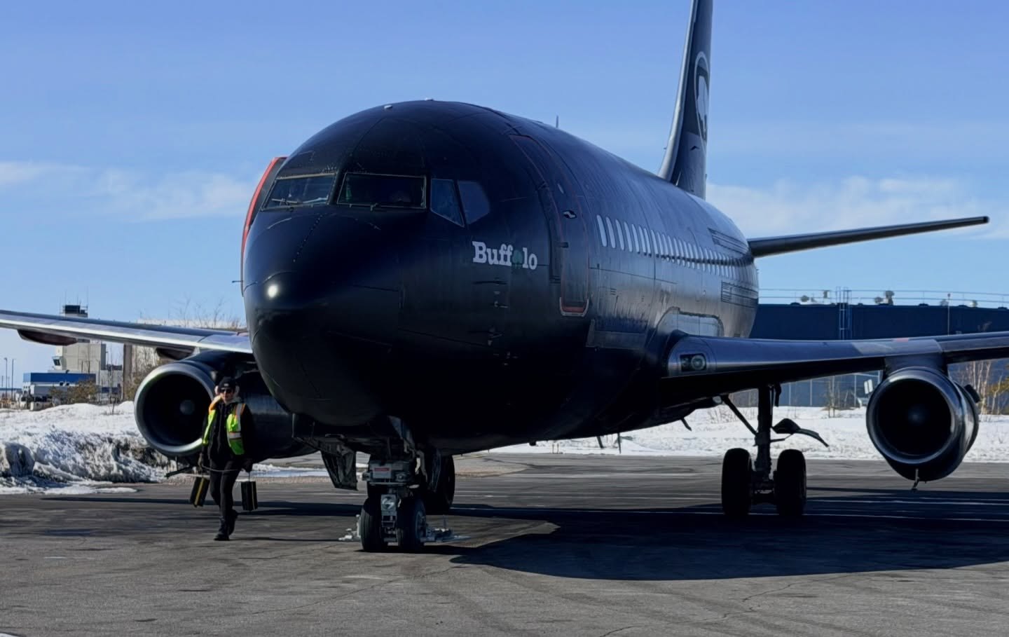 C-GTVO nose-on in its black Buffalo scheme, a rampie walking under the nose
