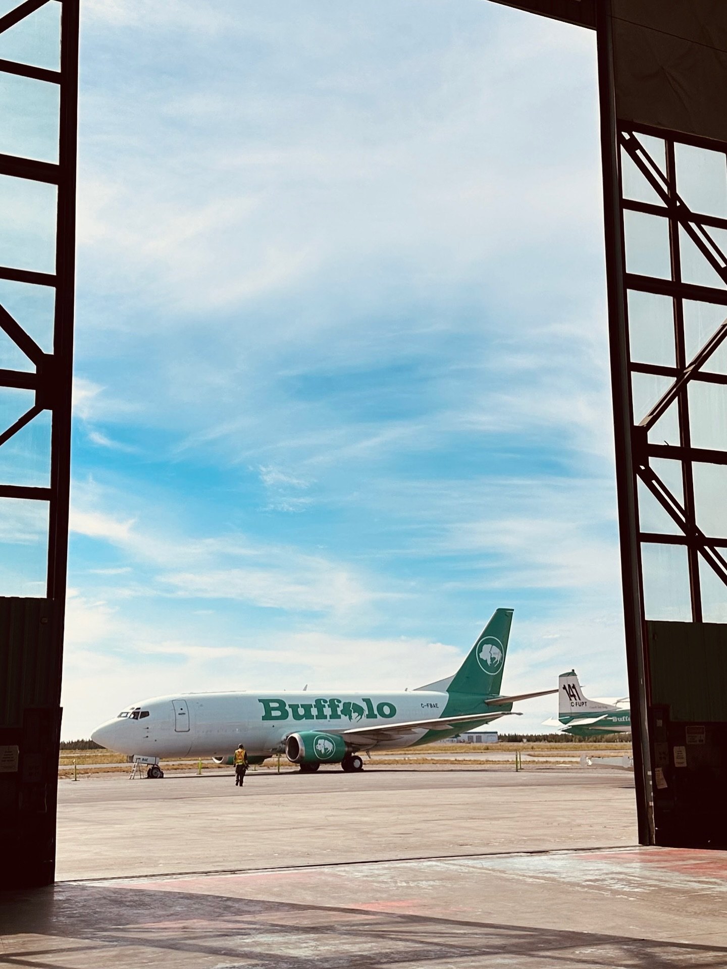 C-FBAE seen through the Yellowknife hangar doors, a Fireboss tail beyond