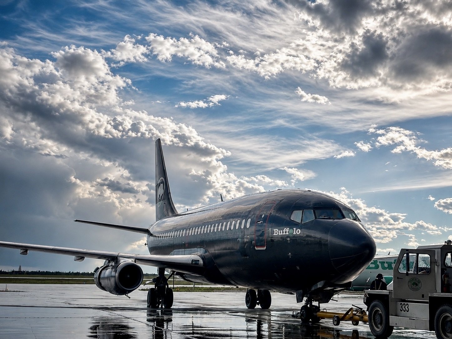C-GTVO under a towering sky on the wet spring ramp, tug alongside