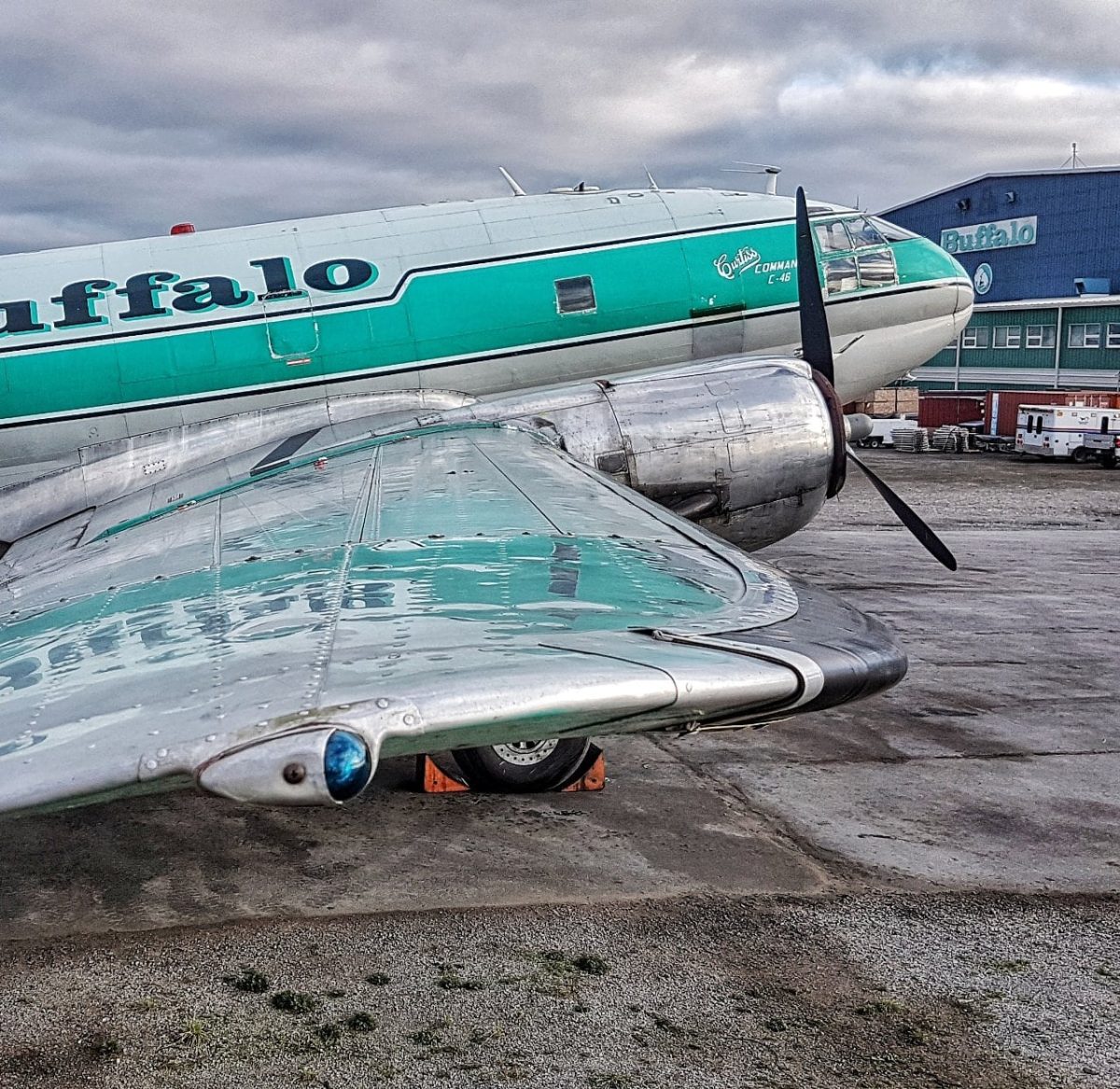 Along the Commando’s wing — Curtiss C-46 nose art, with the Buffalo hangar beyond
