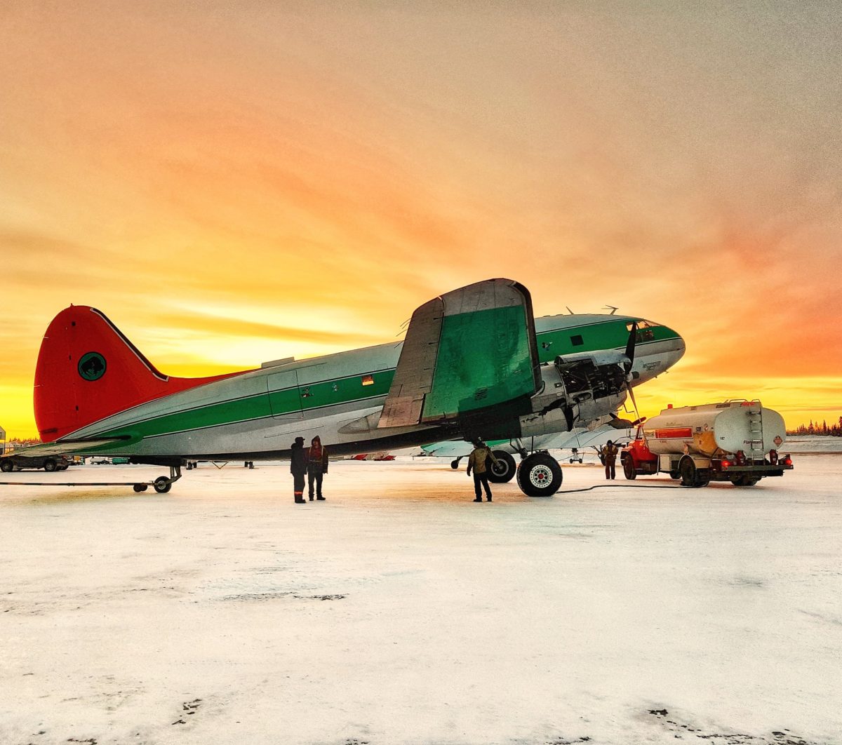 Red-tailed C-46 being fuelled at sunset on a snow-covered ramp