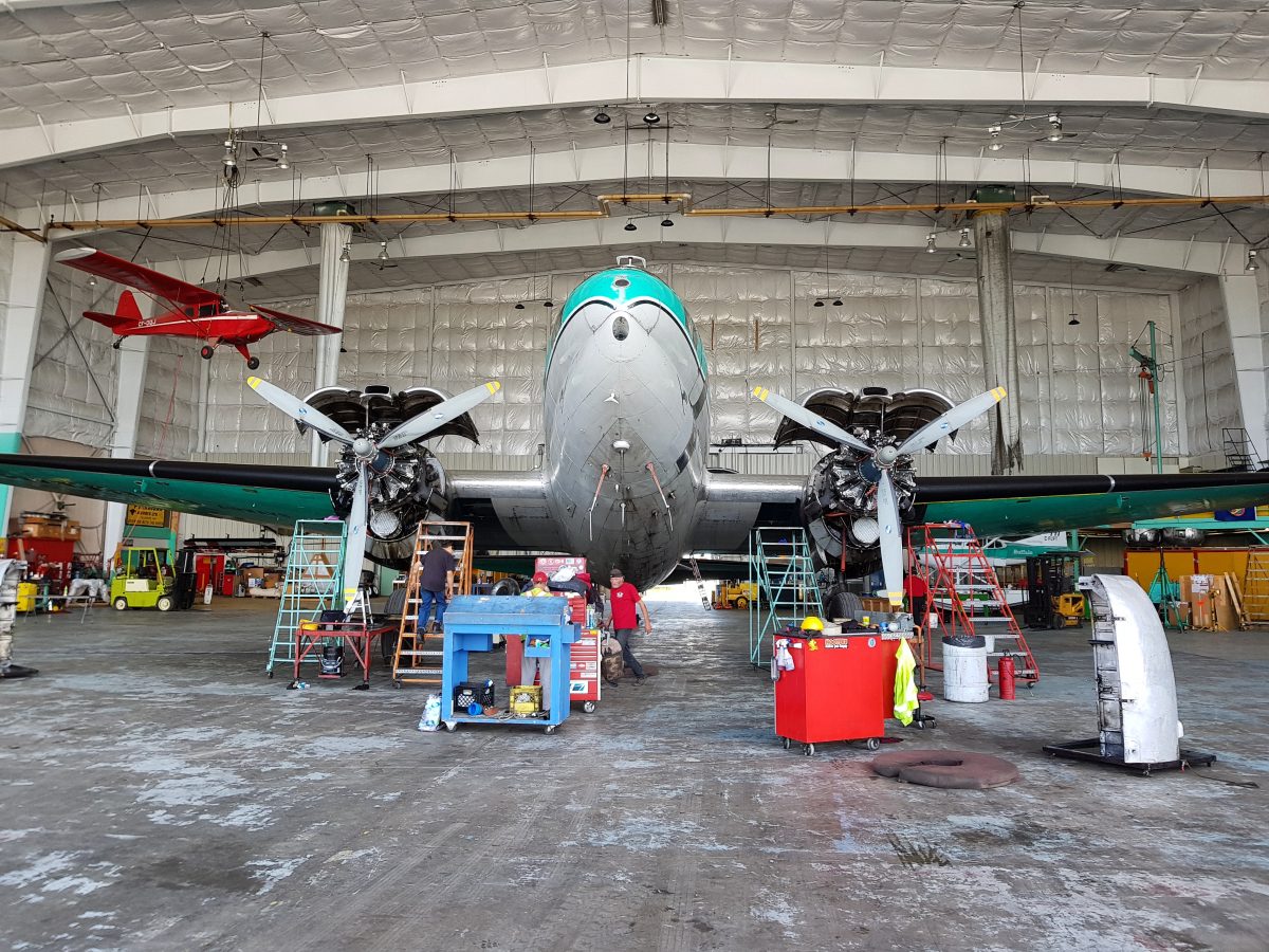 C-46 in the Yellowknife hangar, cowlings open and engineers at work
