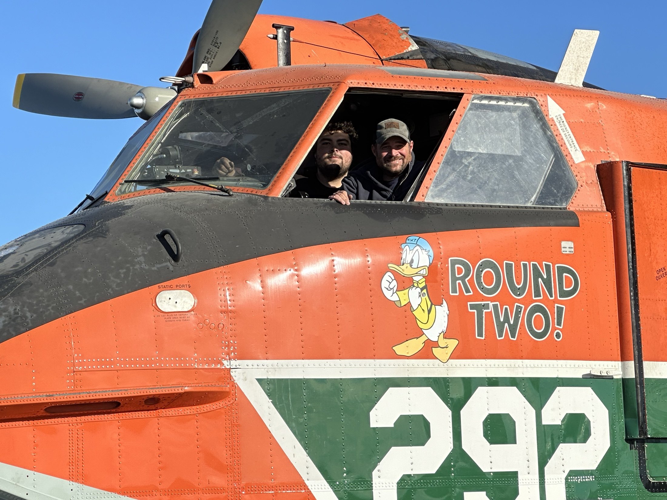Two crew grinning from the cockpit window of Tanker 292, Round Two! nose art below