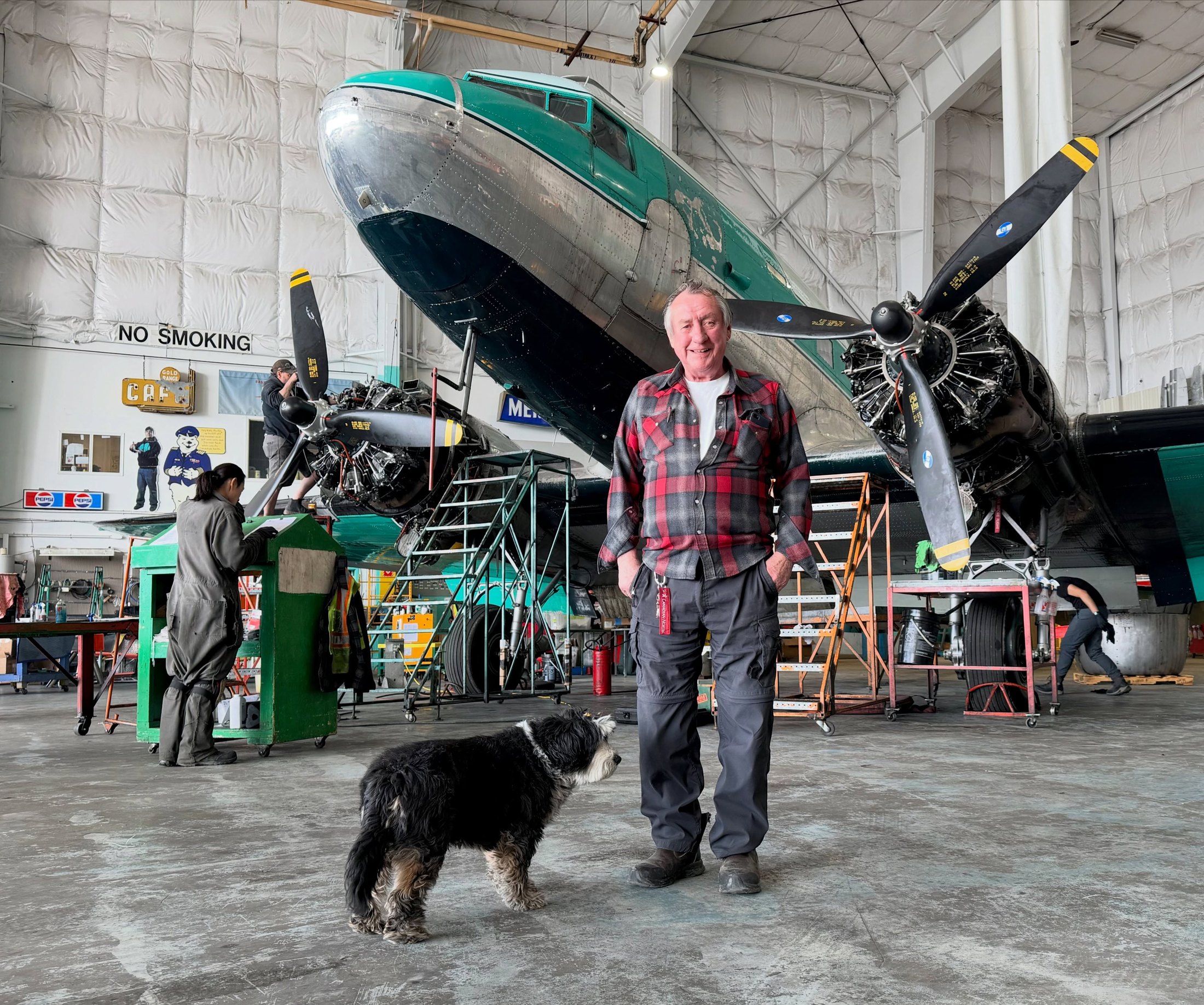 Joe McBryan with the crew and a Buffalo aircraft inside the Yellowknife hangar
